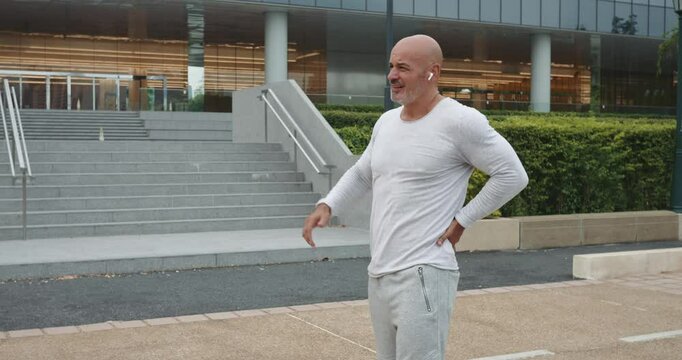 Caucasian white runner was jogging in outdoors when he suddenly felt sharp pain in his back. Sportsman stopped due to severe back pain. Trying to relieve hurt, sportsman carefully stretched his back.