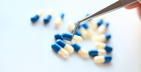 Pharmacist holding tweezers pill closeup medical background concept