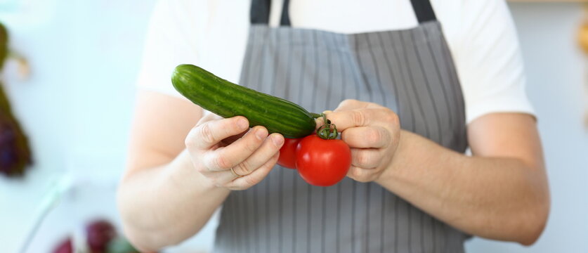 Chef Hands Showing Humorous Vegetable Phalos. Comic Male Joking with Tomato and Cucumber. Man Holding Organic Ingredient Humorously. Professional Culinary Recipe Vlog. Horizontal Photography