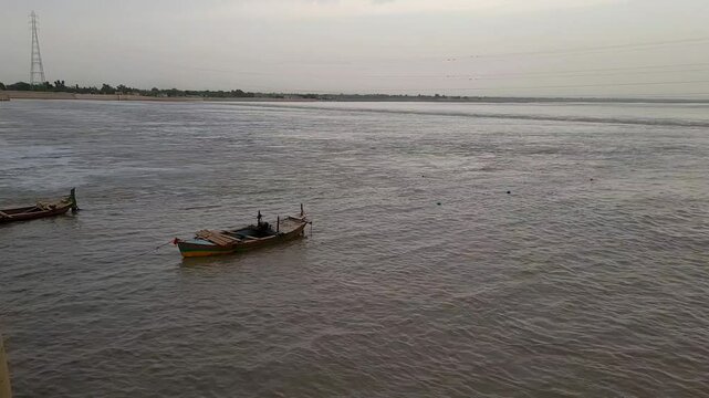 A lone boat sails on the silver surface of the Indus River. 4K