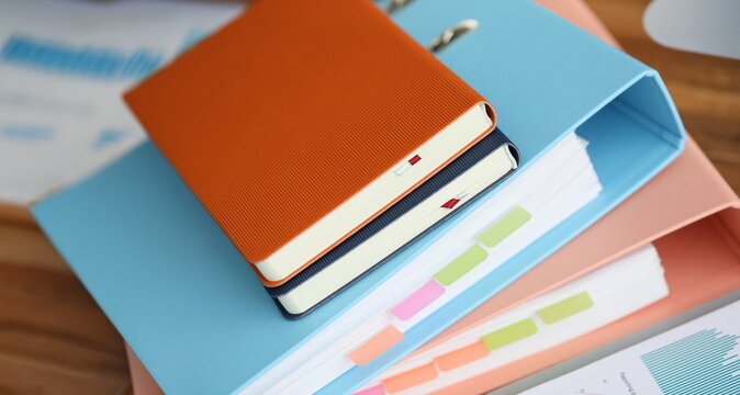 Stack of books with paper foder lie in office against table background. Business education concept.