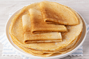 A stack of thin pancakes on a white table