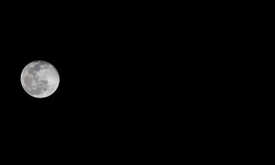 A bright moon on a pitch black sky with copy space on the side for text.