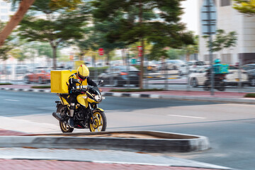 Obraz premium Dubai, Man on a motorcycle for online delivery. Food delivery.Dubai, United Arab Emirates - November 21, 2023.