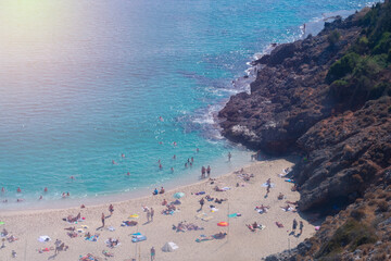 Beautiful top view of blue sea ocean water and beach shore with lots many of people tourists,mountains in summertime and bright sunlight sun.Tourism destination,vacation,holiday