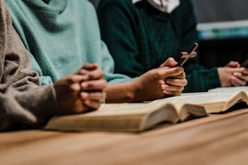 Fototapeta premium A group of people sits together, reading the Bible and praying. Their expressions reflect deep faith and friendship, creating a serene atmosphere filled with love, hope, and spiritual connection.