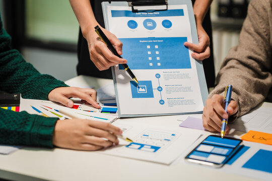Close-up of hands working on UX/UI design at a desk. Papers with wireframes, prototypes, and mockups detail user flows, personas, and A/B testing, ensuring usability and responsive design.