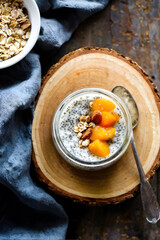 Homemade chia seed pudding with banana, smashed fresh apricot and oat meals on wooden board with copy space. Meal plan concept
