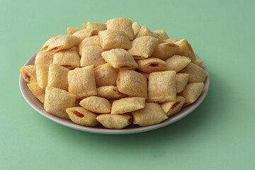 A stack of cookies - corn cushions with strawberry flavored filling on a plate