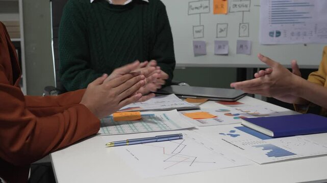 A group of people collaborates around a desk, discussing and reviewing user interface (UI) and user experience (UX) elements. usability, accessibility, and design principles for product development.