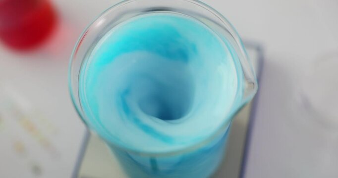 Liquid swirls in flask as reaction of mixed substances. Ongoing reaction between mixed liquids with observable changes in laboratory environment