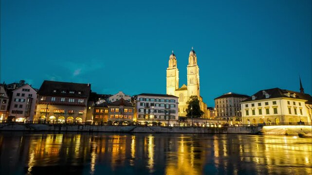 A city with a river running through it and a large church in the background. The sky is blue and the water is calm