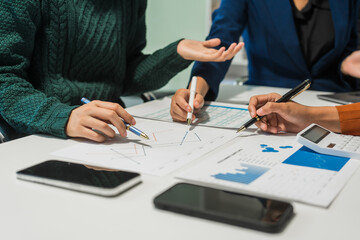 A group of people collaborates around a desk, discussing and reviewing user interface (UI) and user...