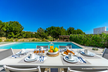 Mesa de desayuno junto a la piscina en una villa en un campo de golf. 