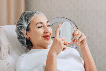 woman carefully observes the effects of her latest skincare treatment, using a mirror to scrutinize her refreshed complexion