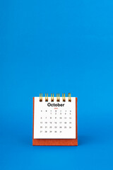 October 2024 white desk calendar on blue background.