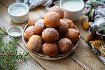 Sweet dessert for breakfast: donuts with powdered sugar on a plate on a wooden background. Close-up