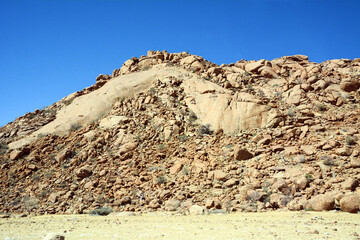 Stone peak on the hill against the background of the blue sky. Tourist destinations and nature