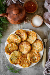 Vegetable pancakes on a beautiful dinner plate for the whole family. Hearty dinner: potato pancakes on a white plate on a gray background. Vertical photo. View from above