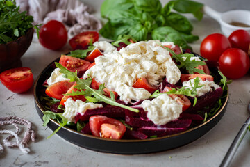 Vegetarian breakfast dish: salad with straticella, cherry tomatoes, arugula, spices and olive oil. Salad with tomatoes and arugula for lunch. Close-up