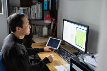 Man working on laptop at home, bar charts displaying on the computer screen.