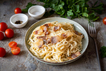 A hearty dinner for the whole family: Italian pasta carbonara in a beautiful plate on a gray background. Close-up