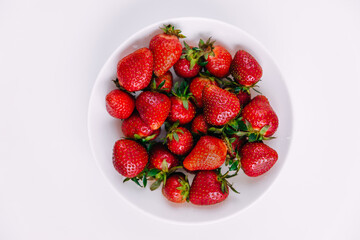 Heap of fresh strawberries in white ceramic bowl on rustic white wooden background