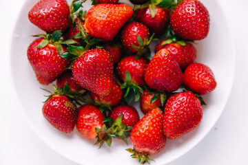 Delicious juicy strawberries on a white plate. Fresh strawberries close-up on a white background.