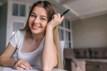 girl holding a pencil in her hand, smiling at the camera.