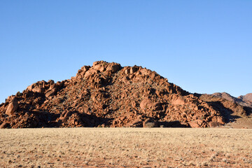 Stone peak on the hill against the background of the blue sky. Tourist destinations and nature