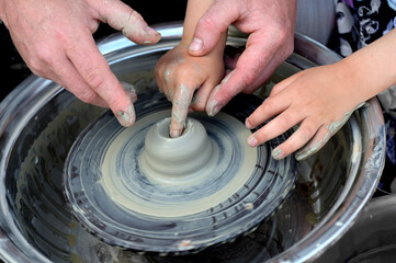 Potter helps to the child at a pottery master class.