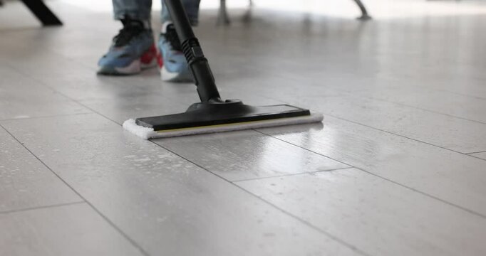 Janitor washes floor with steam mop in house slow motion. Maid cleans dirt form parquet with vapor device at home. Household technology