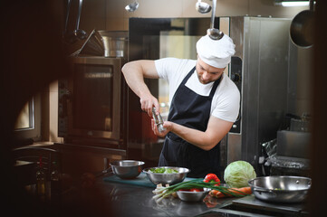 Chef cook in uniform cooking in the big cooker at the restaurant kitchen