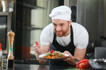 Closeup of a concentrated male chef garnishing food in the kitchen