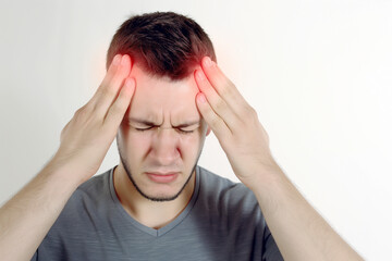 Fototapeta premium Portrait of young man isolated on isolated background suffering from severe headache. Pressing fingers to temples. Closing eyes to relieve pain