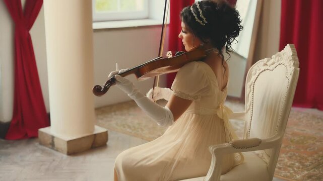 fantasy queen woman violinist playing the violin classic old style. Girl musician sitting on chair classic room art music. White vintage dress, sexy lady back rear view. holiday Viennese ball party
