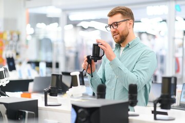 A man chooses a professional microphone to record a video blog. Electronics store