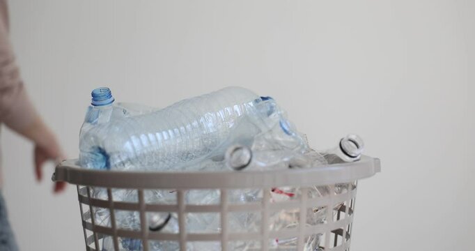 Woman throws used plastic bottle into garbage bin slow motion. Lady sorts waste for recycling materials. Sustainable lifestyle habits