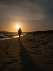 person walking on the beach at sunset