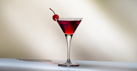 Manhattan alcoholic cocktail drink with whiskey, red vermouth and cherry in martini glass. Beige background