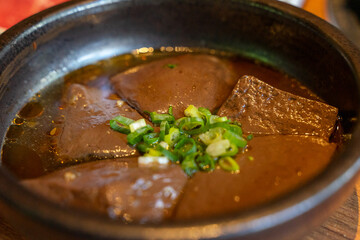 A hearty serving of duck blood tofu sits in a steaming hotpot, enriched with flavorful broth and a...