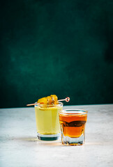 Alcoholic cocktail drink from cucumber pickle and whiskey in shot glasses. Dark green background © 5ph