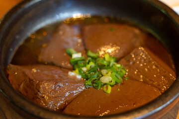 A hearty serving of duck blood tofu sits in a steaming hotpot, enriched with flavorful broth and a medley of spices. This authentic Asian delicacy boasts a silky texture and rich, savory taste