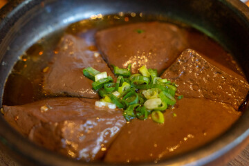 A hearty serving of duck blood tofu sits in a steaming hotpot, enriched with flavorful broth and a medley of spices. This authentic Asian delicacy boasts a silky texture and rich, savory taste