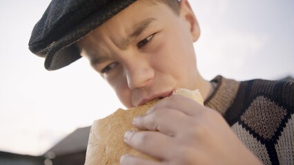 Little boy drink milk and eat a loaf of bread in a village at sunset