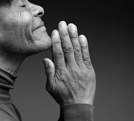 Fototapeta premium man praying to god with hands together Caribbean man praying with black background with people stock photo