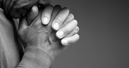 man praying to god with hands together Caribbean man praying with black background with people stock photo