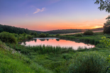 Picturesque sunset over a small lake near the forest