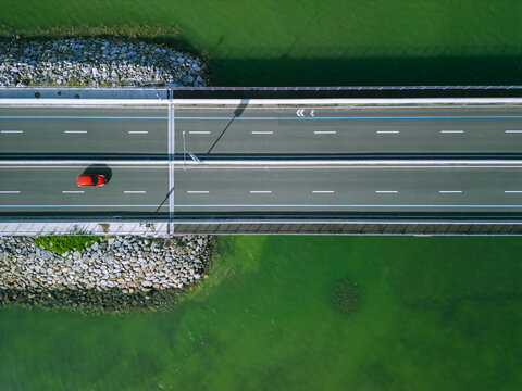 a drone shot of a red car passing by a bridge over the sea in Cebu, Philippines