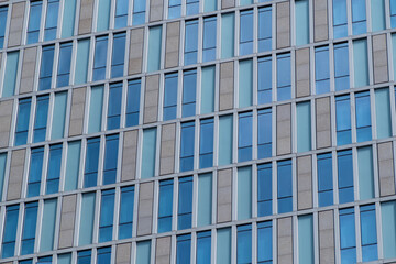 Fototapeta premium A detailed view of a building facade featuring a repetitive pattern of windows and panels.
